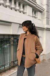 a lady in a brown wool jacket and a pair of grey pants
